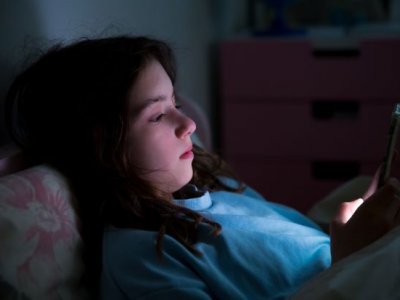 a girl's face is illuminated by the light of a phone screen